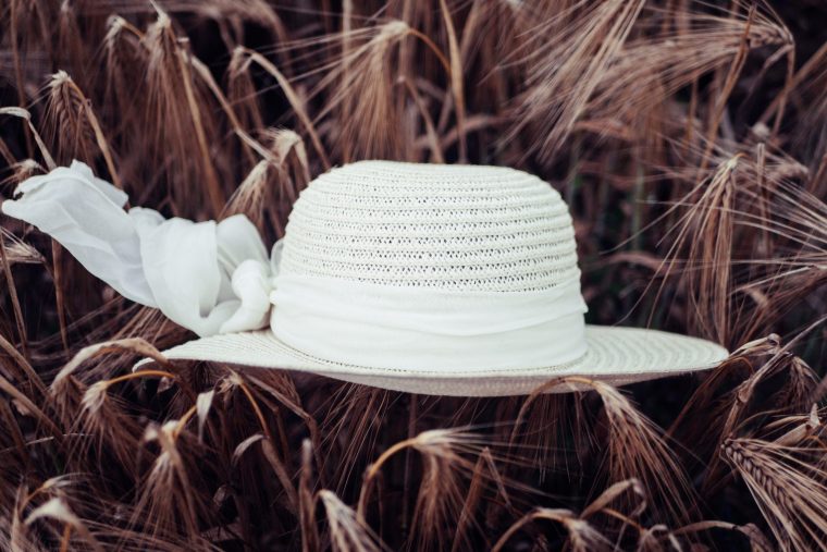 white sun hat on brown dried leaves